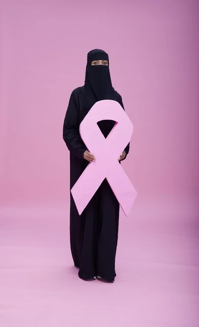 امرأة سعودية بالنقاب تحمل شعار التوعية بسرطان الثدي