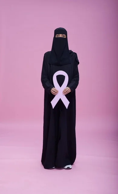 امرأة سعودية بالنقاب تحمل شعار التوعية بسرطان الثدي
