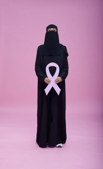 امرأة سعودية بالنقاب تحمل شعار التوعية بسرطان الثدي