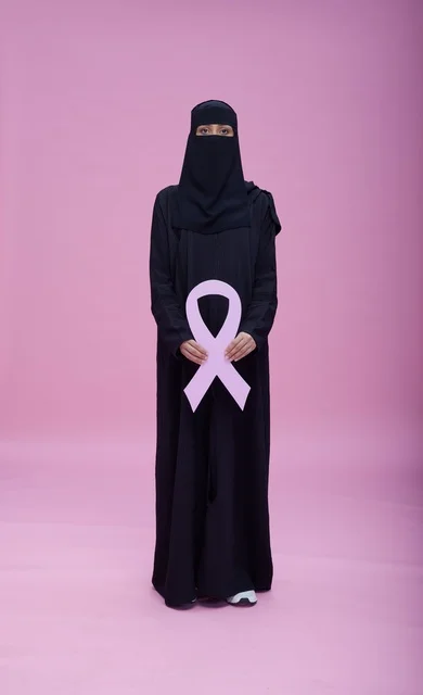 امرأة سعودية بالنقاب تحمل شعار التوعية بسرطان الثدي