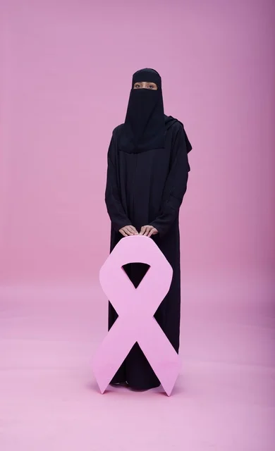 امرأة سعودية بالنقاب تحمل شعار التوعية بسرطان الثدي