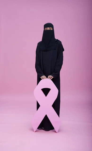 امرأة سعودية بنقاب تحمل شعار التوعية بسرطان الثدي