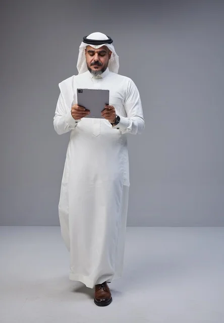 Saudi Man in Traditional Dress Using Tablet