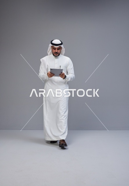 Saudi Man in Traditional Thobe Using Digital Tablet