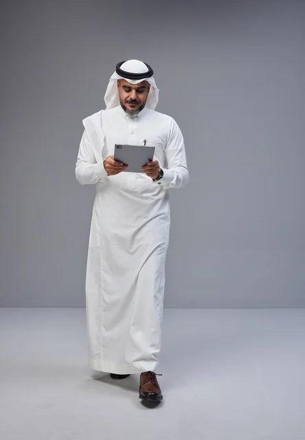 Saudi Man in Traditional Thobe Using Tablet in Studio