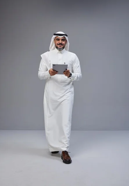 رجل سعودي بالزي التقليدي يستخدم جهازاً لوحياً
