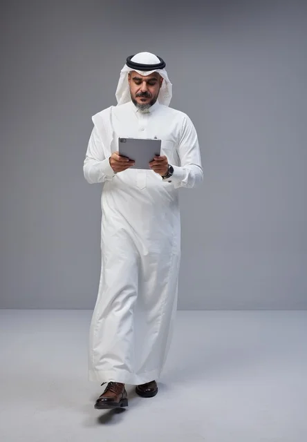Saudi Man in Traditional Thobe Using Tablet in Studio
