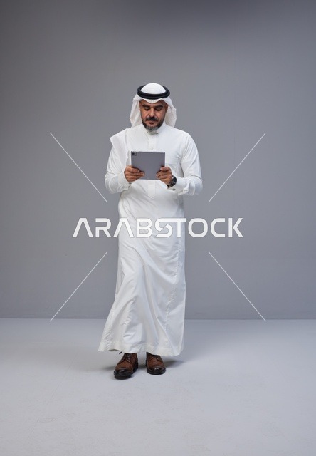Saudi Man in Traditional Thobe Using Digital Tablet