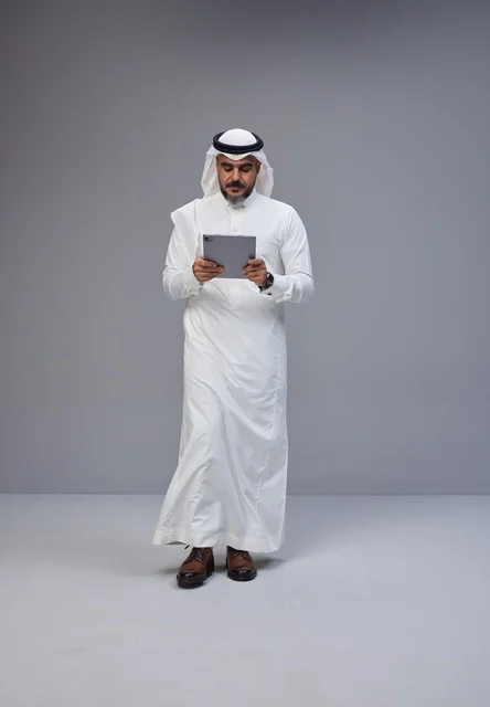 Saudi Man in Traditional Thobe Using Digital Tablet