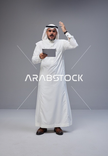 Saudi Man in Traditional Thobe Using Tablet with Frustration
