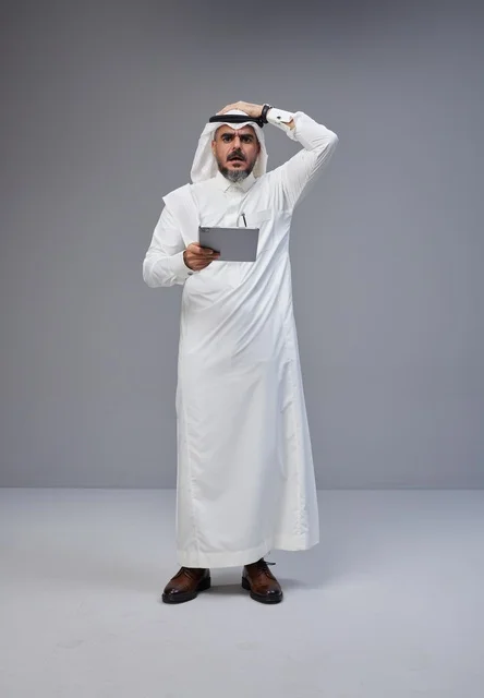 Shocked Saudi Man Holding Tablet in Traditional Dress