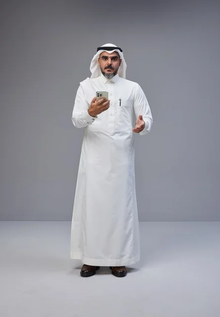 Saudi Man in Traditional Thobe Using Smartphone