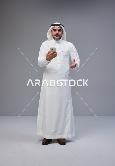 رجل سعودي بالزي التقليدي يستخدم الهاتف الذكي