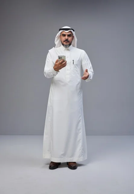 رجل سعودي بالزي التقليدي يستخدم الهاتف الذكي