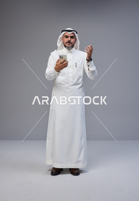 Saudi Man in Traditional Thobe Using Smartphone