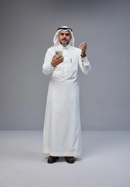 Saudi Man in Traditional Thobe Using Smartphone