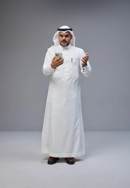 Saudi Man in Traditional Thobe Using Smartphone Studio
