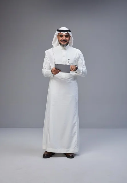 رجل سعودي بالزي التقليدي يستخدم جهاز لوحي