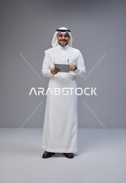 Saudi Man in Traditional Thobe Using Digital Tablet