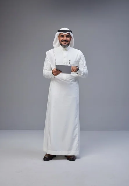 رجل سعودي بالزي التقليدي يستخدم جهازاً لوحياً