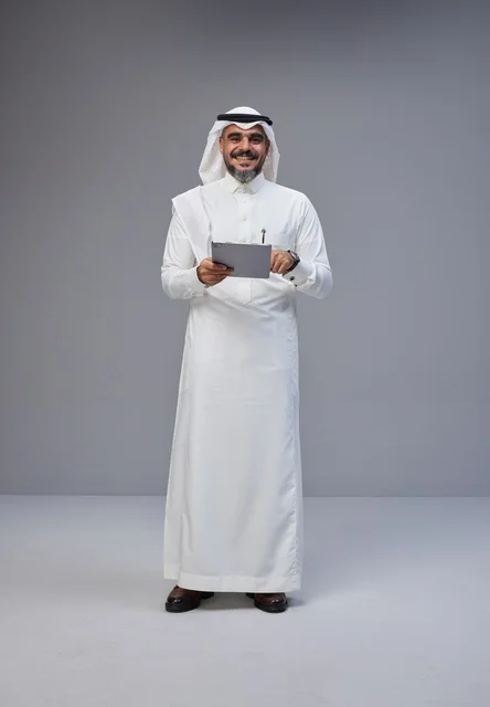 رجل سعودي بالزي التقليدي يستخدم جهازاً لوحياً