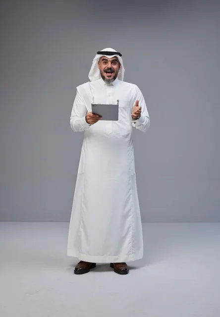 رجل سعودي مندهش يمسك جهاز لوحي في الاستوديو