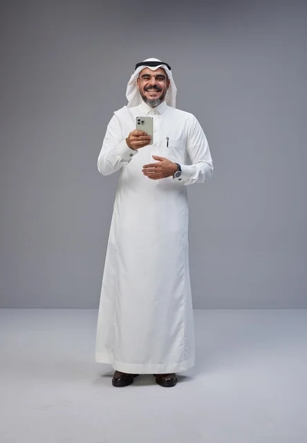 رجل سعودي بالزي التقليدي يستخدم الهاتف الذكي