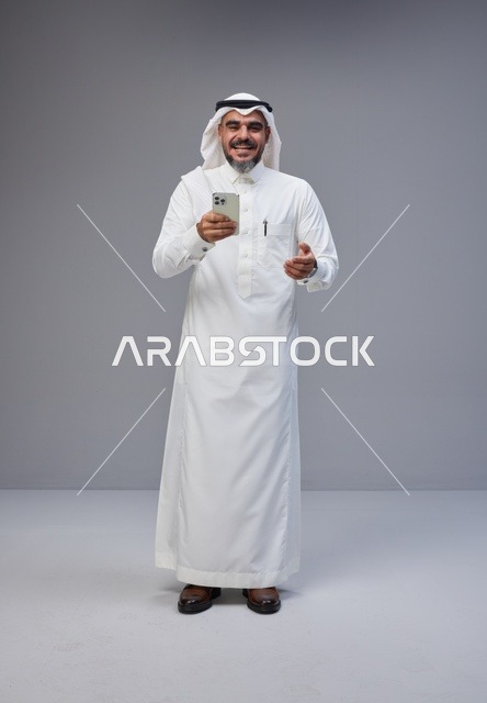 رجل سعودي بالزي التقليدي يستخدم الهاتف الذكي