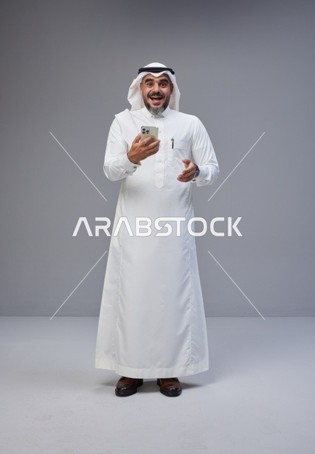 رجل سعودي بالزي التقليدي يستخدم الهاتف الذكي