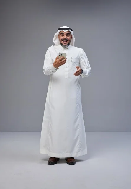 رجل سعودي بالزي التقليدي يستخدم الهاتف الذكي