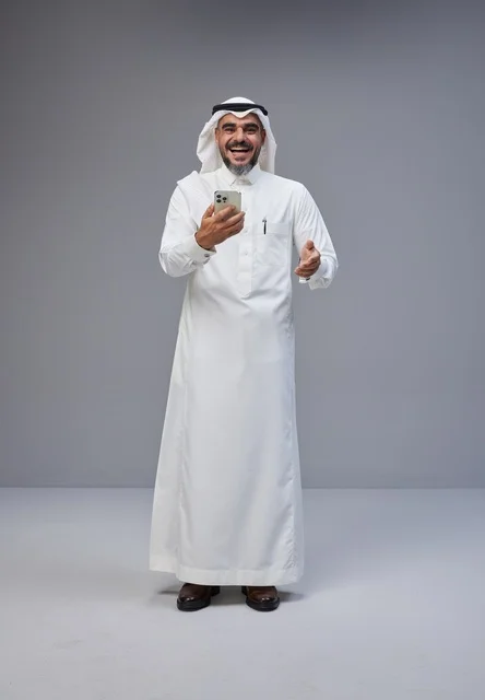 رجل سعودي بالزي التقليدي يستخدم الهاتف الذكي
