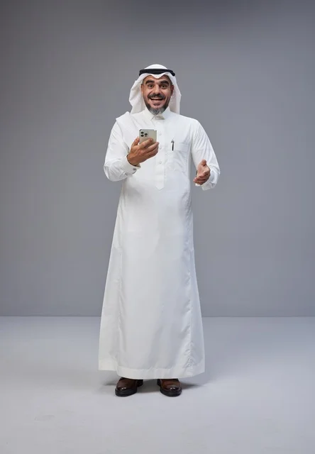 رجل سعودي بالزي التقليدي يستخدم الهاتف الذكي