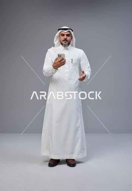 رجل سعودي بالزي التقليدي يستخدم الهاتف في الاستوديو