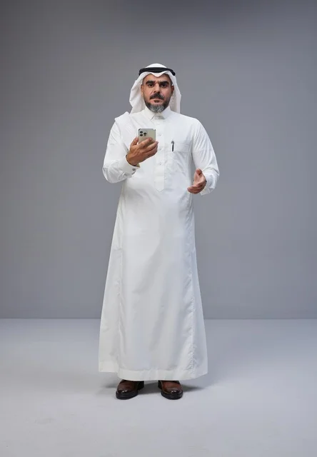 رجل سعودي بالزي التقليدي يستخدم الهاتف في الاستوديو