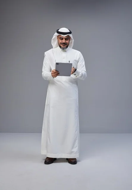 Saudi Man in Traditional Thobe Using Digital Tablet