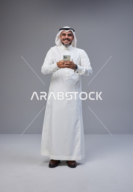 رجل سعودي بالزي التقليدي يستخدم الهاتف الذكي