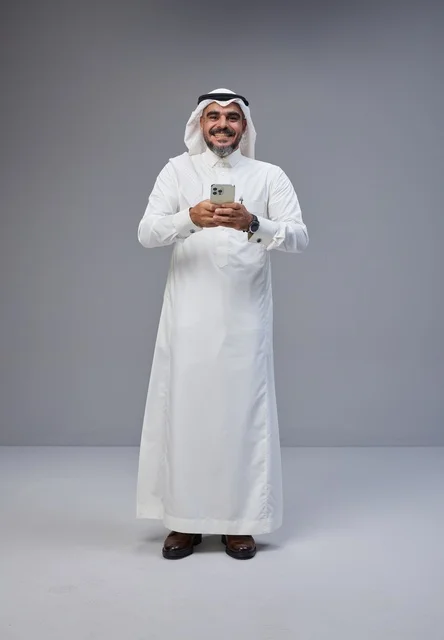 Saudi Man in Traditional Thobe Using Smartphone