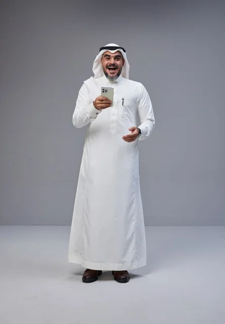 Excited Saudi Man in Traditional Thobe Using Smartphone
