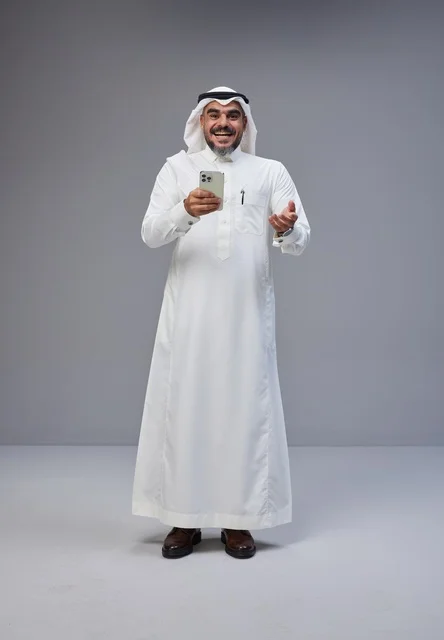 رجل سعودي بالزي التقليدي يستخدم الهاتف الذكي