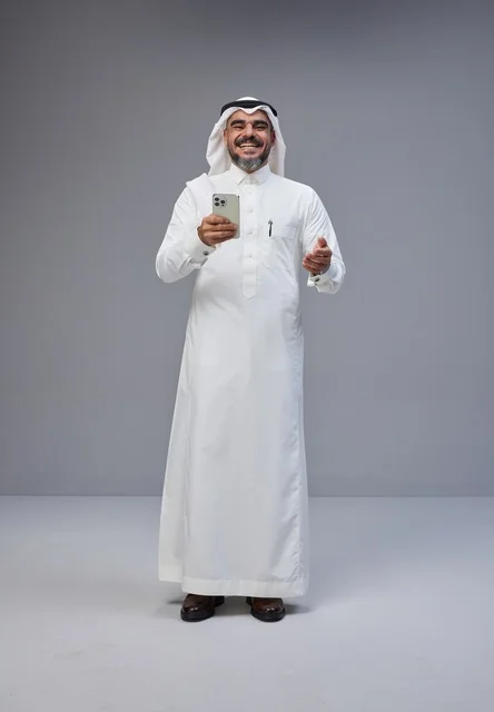 رجل سعودي بالزي التقليدي يستخدم هاتف ذكي