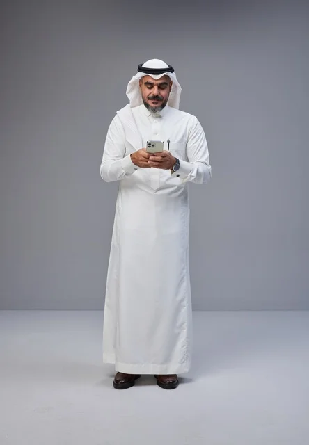 Saudi Man in Traditional Dress Using Smartphone in Studio