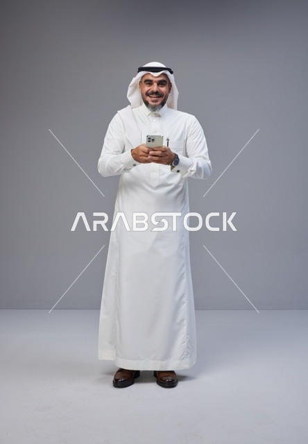 رجل سعودي بالزي التقليدي يستخدم الهاتف الذكي