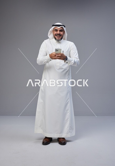 رجل سعودي بالزي التقليدي يستخدم الهاتف الذكي