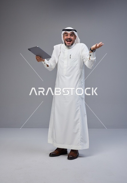 Saudi Man in Traditional Thobe Holding Tablet Successfully
