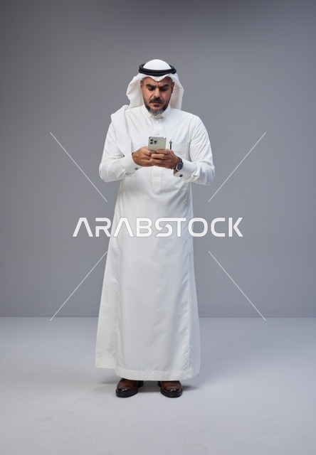 Saudi Man in Traditional Thobe Using Smartphone