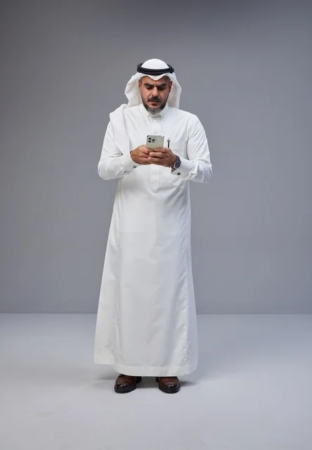 Saudi Man in Traditional Thobe Using Smartphone