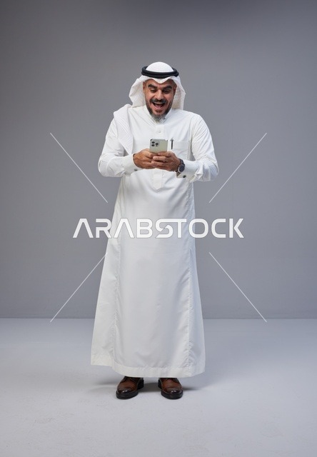 Surprised Saudi Man with Smartphone in Traditional Thobe