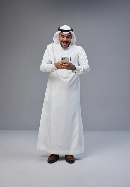 رجل سعودي بالزي التقليدي متفاجئ باستخدام الهاتف الذكي