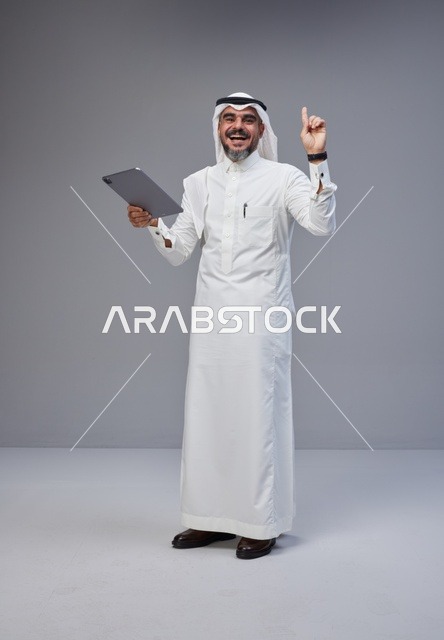 Smiling Saudi Man Pointing Up with Tablet in Studio