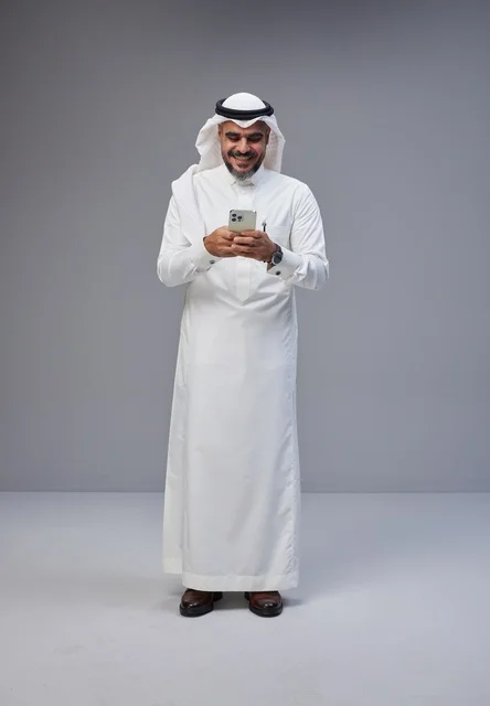 رجل سعودي بالزي التقليدي يستخدم الهاتف في الاستوديو